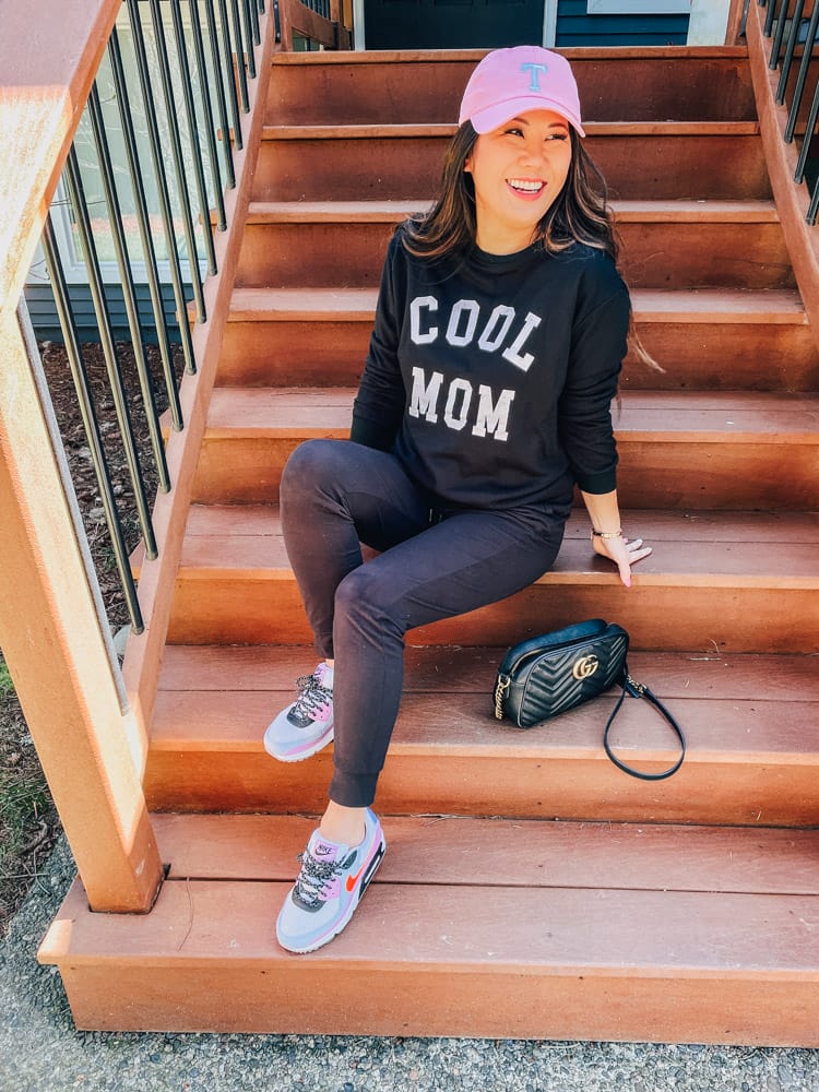 woman wearing cool mom shirt and black joggers with sneakers on the steps