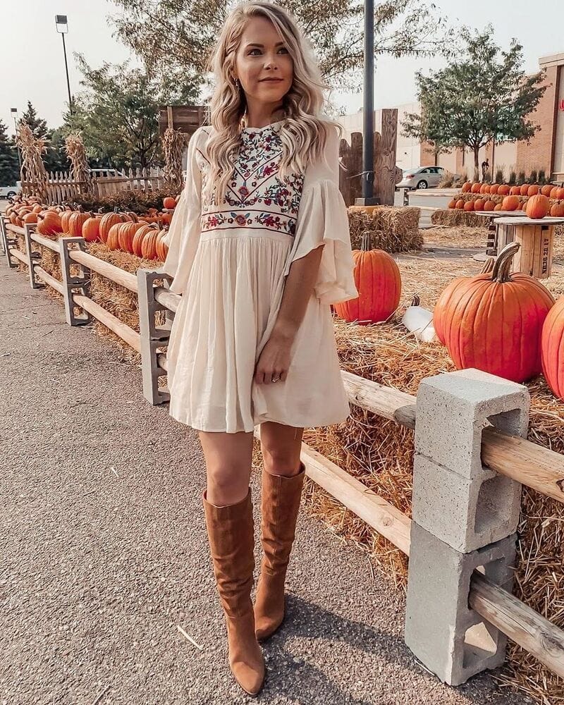 woman in pumpkin patch wearing boho dress and boots