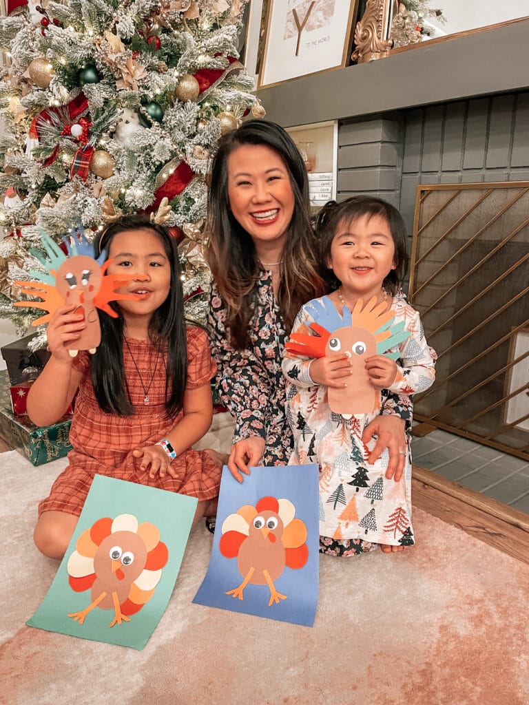 mom and daughters holding home made turkey crafts