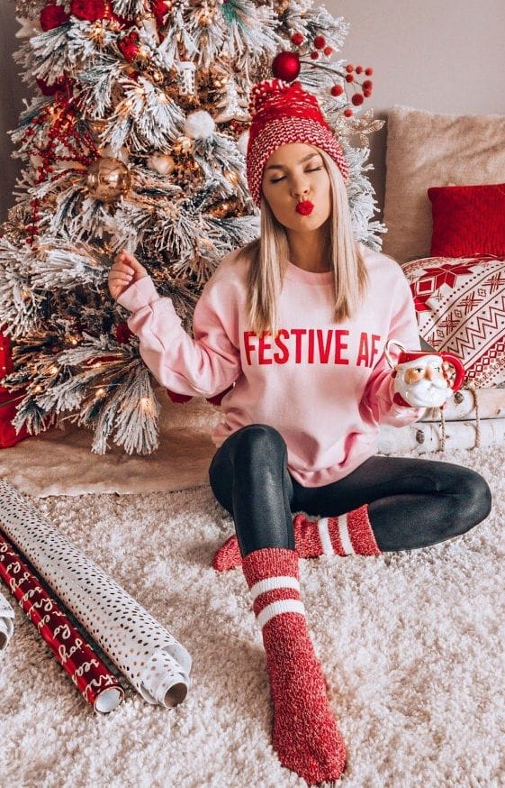 Girl wearing Festive AF sweatshirt in front of Christmas tree